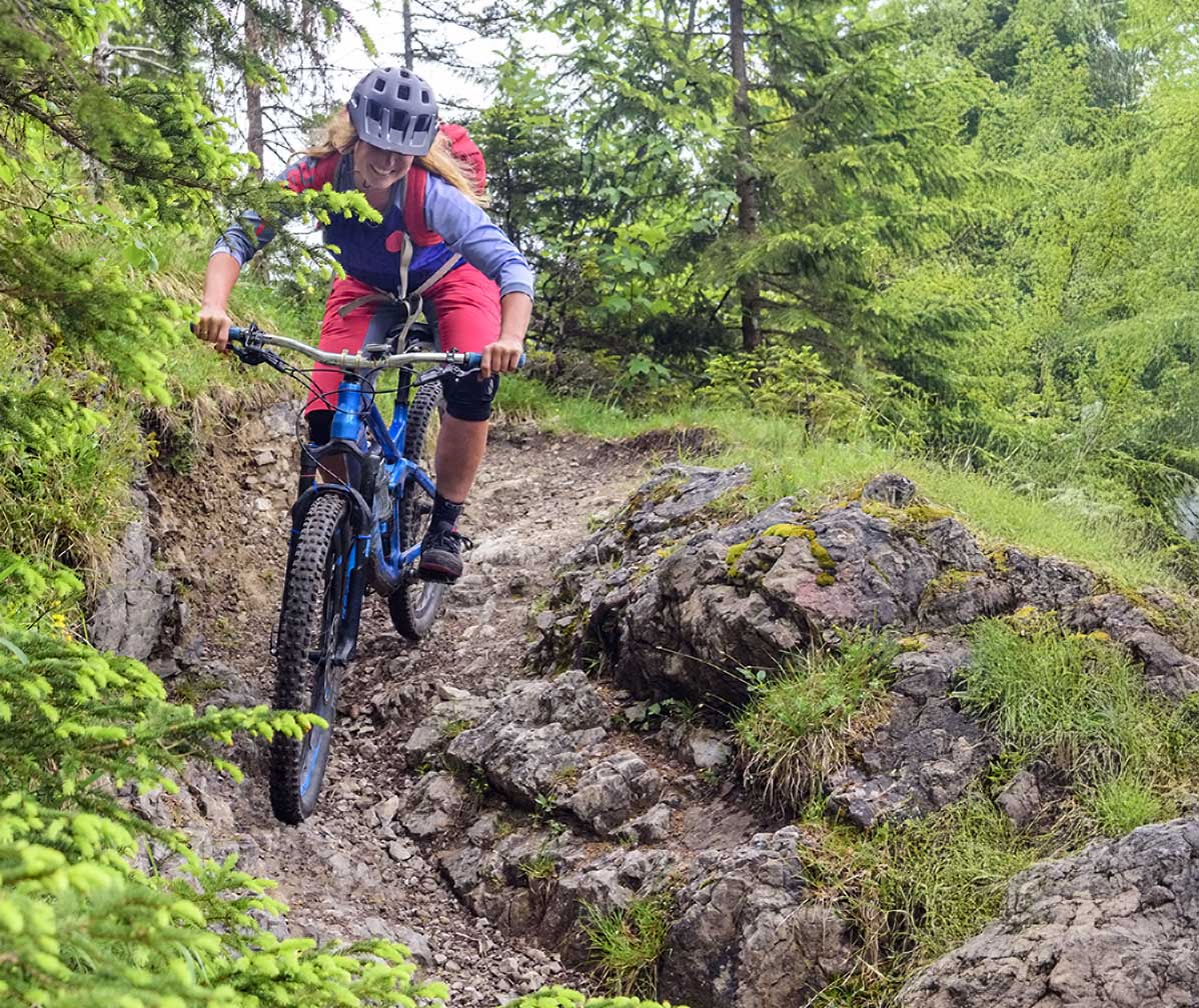 Mountain biker riding a technical enduro trail with rocks and roots during training