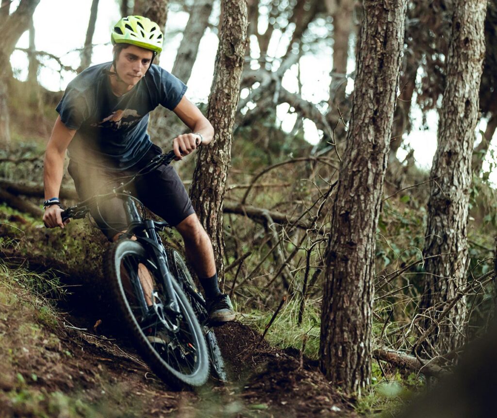 Enduro mountainbiker rijdt een technische afdaling door het bos tijdens gerichte enduro training