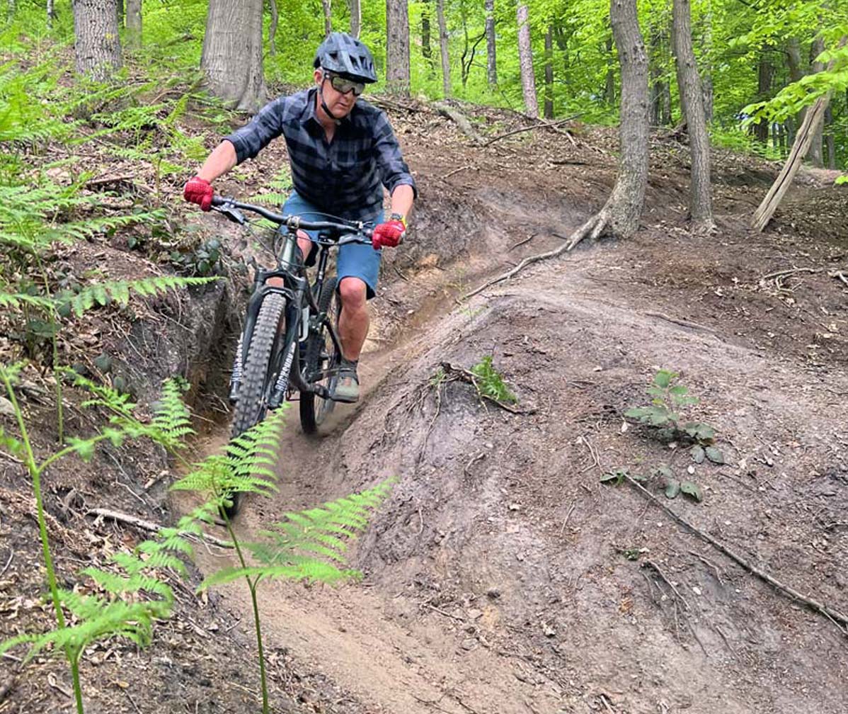 Mountainbiker traint techniek en controle op een technische trail tijdens Flow Ride van PeakFlow MTB